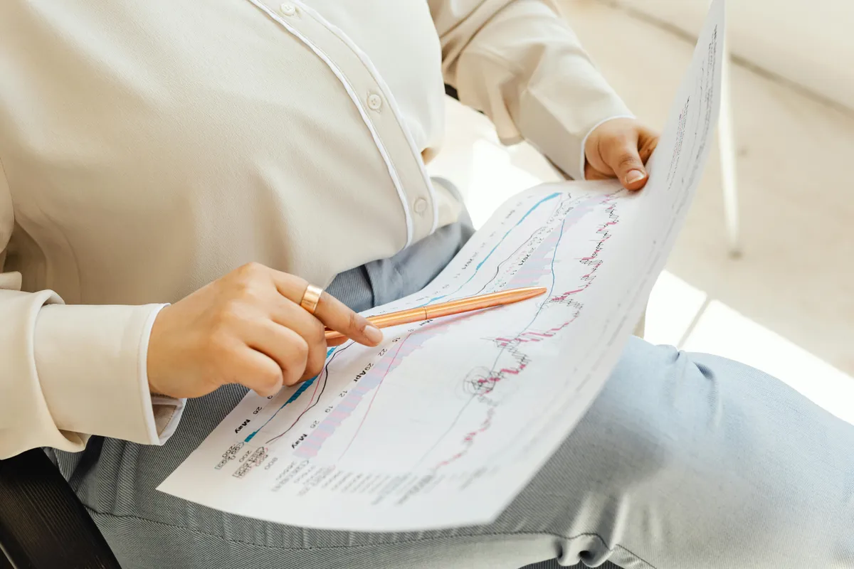 A financial professional studying a printed stock market chart with a pen, focused on long-term trends