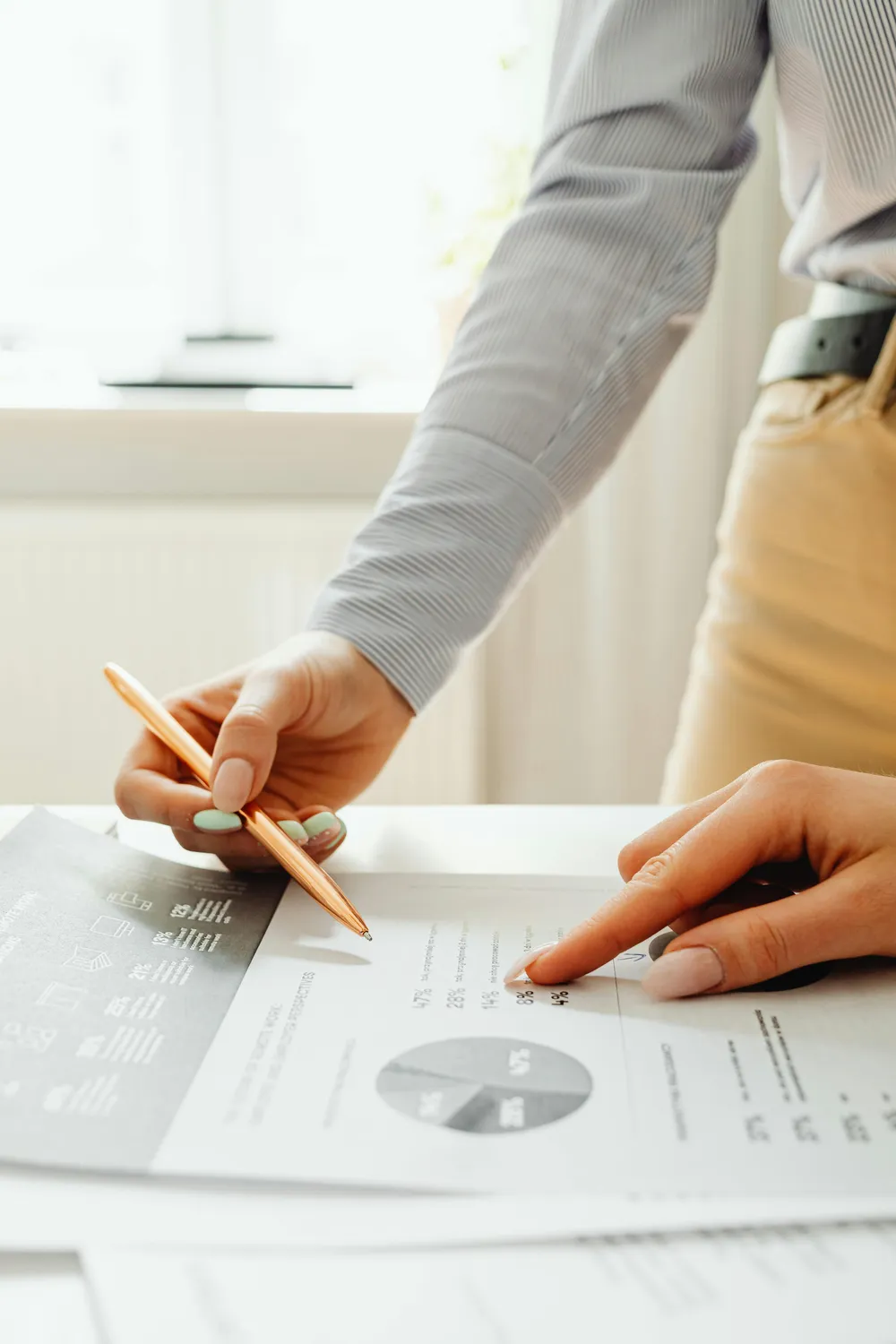 An advisor reviewing a financial plan and analytics report with a client, pointing to figures with a pen