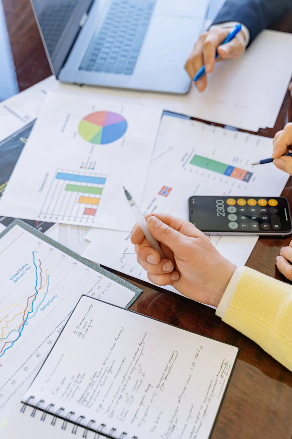 Two people reviewing financial charts, notes, and a calculator while assessing coverage needs during an insurance planning session