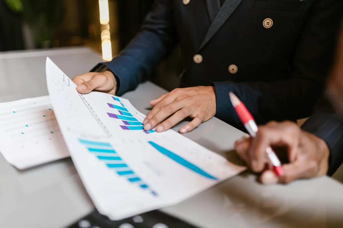 An advisor reviewing investment performance charts on a printed report while taking notes